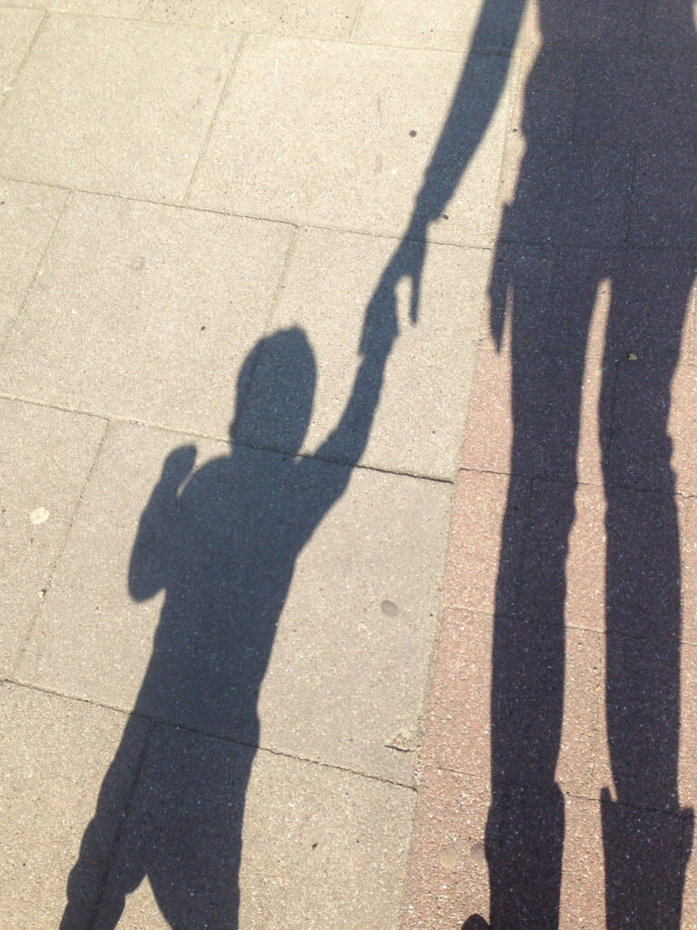 schattenbild auf gehweg, kleinkind an der hand seiner mama