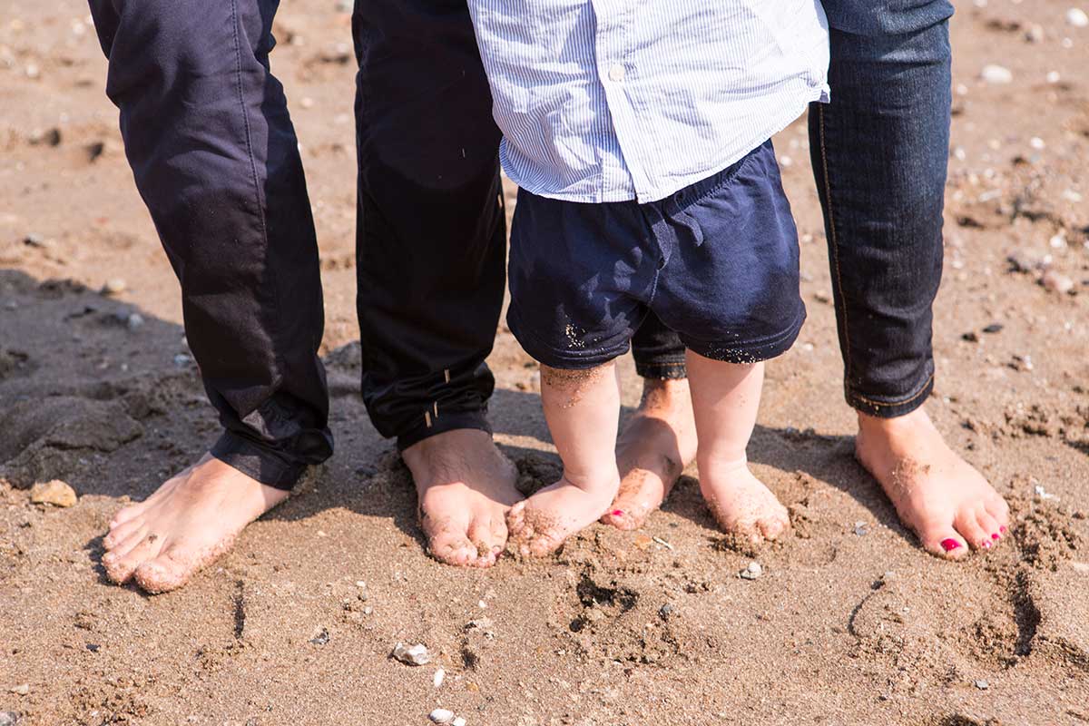 füße von eltern und baby am elbstrand