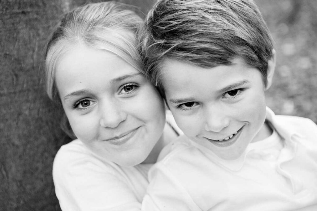 grundschulkinder im wald, ein nahes portrait von bruder und schwester, kuschelnd